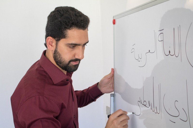 Abdalah escribiendo en árabe en la pizarra durante una clase en Santiago de Chile